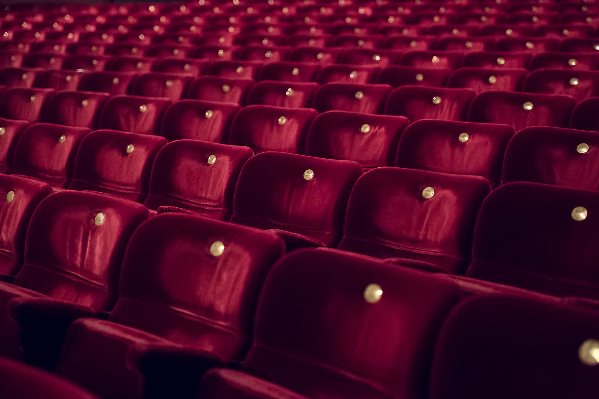 Röda teaterstolar i en tom teatersalong.