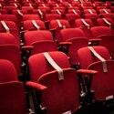 Teatersalong med röda stolsrader, varav flera är täckta med med tejp. Det är en teatersalong med restriktioner för att hindra att människor sitter för nära varandra under pandemin.
